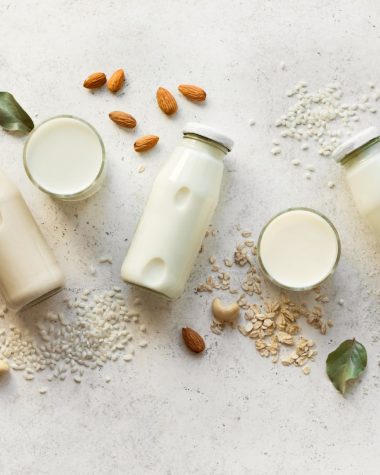 Wegańskie mleko roślinne w różnych postaciach ułożonych na stole.