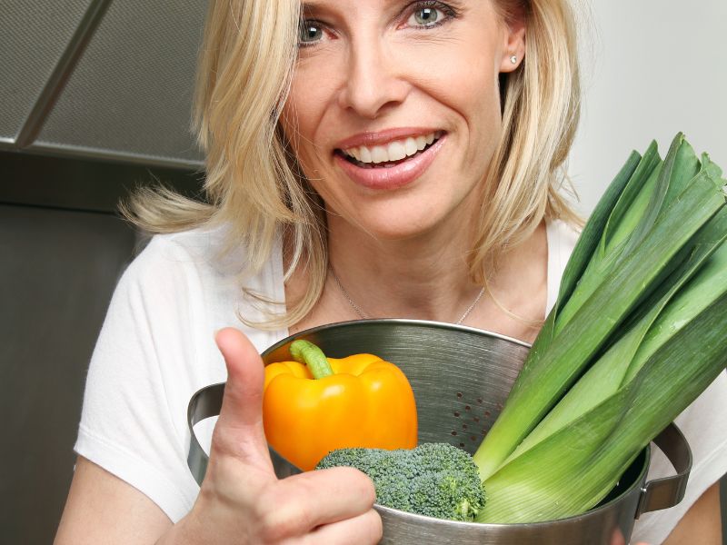Czy wegetarianie żyją dłużej? Na zdjęciu kobieta wegetarianka gotuje.