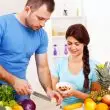 Małżeństwo, które praktykuje wegetarianizm, przygotowuje w kuchni posiłek.